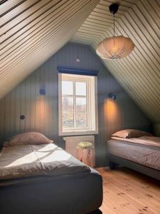 a attic room with two beds and a window at Jóhannshús- tradational Icelandic house in Hrepphólar