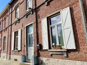 a brick building with two windows and a door at Les Volets Blancs in Braine-le-Comte