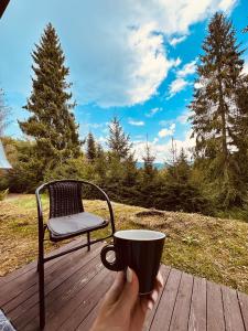 a person holding a cup of coffee on a wooden deck at Chata Kokava Línia tour 2 in Kokava na Rimavica