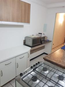 uma cozinha com um fogão e um micro-ondas no balcão em Quarto no Jd. Satélite - Excelente localização na Zona Sul em São José dos Campos