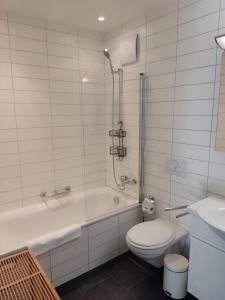 y baño con bañera, aseo y lavamanos. en Superior Apartment en Engelberg