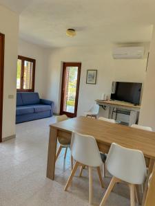 a living room with a wooden table and white chairs at Comoda villetta con giardino in San Teodoro