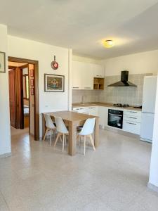a kitchen with a wooden table and white appliances at Comoda villetta con giardino in San Teodoro