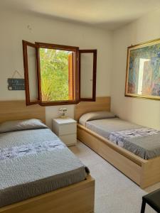 a bedroom with two beds and a window at Comoda villetta con giardino in San Teodoro