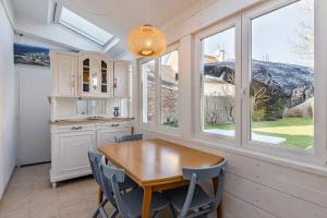 cocina con mesa de madera, sillas y ventanas en Maison des Embruns - 2 chambres et Jardin clos, en Saint-Malo