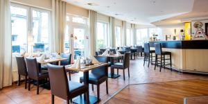 un comedor con mesas, sillas y ventanas en Hotel Hangelar, en Sankt Augustin