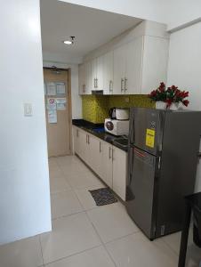 a kitchen with white cabinets and a stainless steel refrigerator at Sea Residences MOA -PaulJade Place in Manila