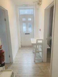ein weißes Zimmer mit einem Tisch und einer Tür in der Unterkunft Bike Park Cottage Sleeps 5 with Pet in Merthyr Tydfil