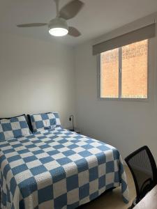 um quarto com uma cama com um cobertor xadrez azul e branco em Apê da Sil em São Paulo