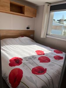 a bedroom with a bed with red flowers on it at Mobil home neuf 6 p à Hyères dans camping 4 étoiles Les Pins Maritimes in Hyères