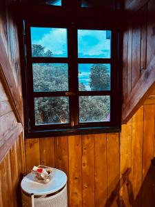 een raam in een houten kamer met een tafel en een kruk bij Cabaña Palo Alto in Barva
