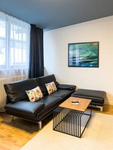 a living room with a black leather couch and a table at Exklusives Leipzig City Apartment Aurora in Leipzig