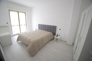 a white bedroom with a bed and a window at Il nascondiglio in San Ferdinando di Puglia