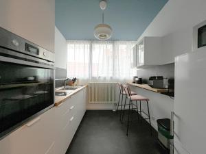 a kitchen with white cabinets and pink stools in it at Exklusives Leipzig City Apartment Aurora in Leipzig