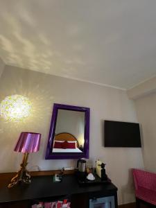 um quarto com um espelho e uma mesa com um candeeiro em Delle Nazioni Milan Hotel em Milão