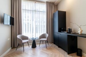 a room with a desk and two chairs and a window at SAYŌ Boutique Hotel in Scheveningen