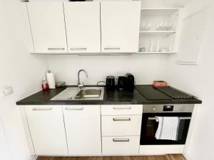 a small kitchen with white cabinets and a sink at StayHere Central City Studio 13 - contactless Self-Check-IN in Graz