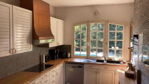 a kitchen with white cabinets and a large window at Gîte du Grand Sancerrois in Jars