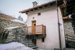 a house with a wooden balcony on the side of it at Lo Mieton - Affitti Brevi Italia in Champoluc