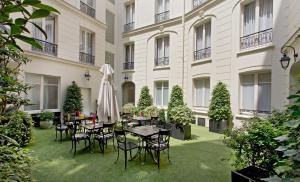 einen Innenhof mit Tischen und Stühlen vor einem Gebäude in der Unterkunft Elysees Apartments in Paris