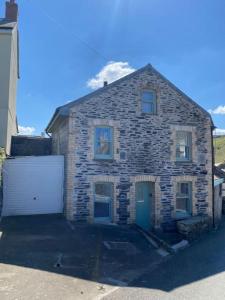 a brick house with a large white garage at Atlantic Cottage Port Isaac 2 bedroom with parking in Port Isaac