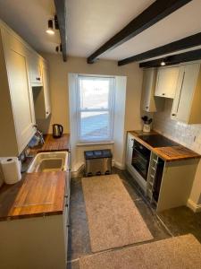a small kitchen with white cabinets and a window at Atlantic Cottage Port Isaac 2 bedroom with parking in Port Isaac