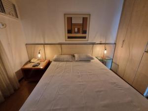 um quarto com uma grande cama branca e uma mesa de cabeceira em Flat Pancetti em Belo Horizonte