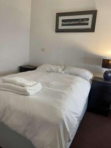 een bed met witte lakens en een foto aan de muur bij Spacious flat next to central station in Glasgow