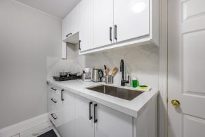 a kitchen with white cabinets and a sink at Charming 1BD Getaway - Unwind Near Niagara Falls in Niagara Falls