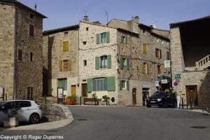 an old stone building with cars parked in front of it at Gites Terre et Ciel in Largentière
