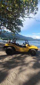 un jeep amarillo estacionado en una playa cerca del agua en Suítes no paraíso da Ilhabela, en Ilhabela