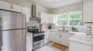 uma cozinha com armários brancos e um frigorífico de aço inoxidável em Modern Chateau Remodeled Home Close to Downtown em Mobile