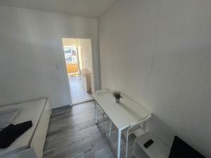 FEE Apartment 1 Bremerhaven في برمرهافن: غرفة بيضاء مع طاولة وأريكة