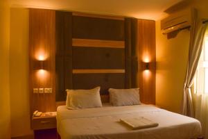 1 dormitorio con 1 cama con sábanas blancas y ventana en Lisgewann Global Hotel, en Ijesa-Tedo