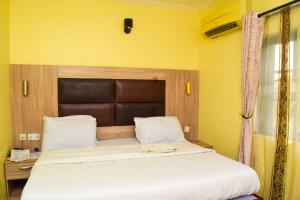 a large bed in a room with yellow walls at Lisgewann Global Hotel in Ijesa-Tedo