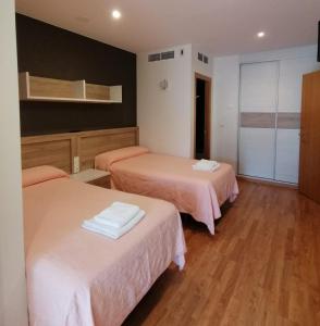 a hotel room with two beds with pink sheets at Apartamentos Rompeolas in Burela de Cabo