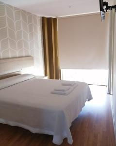a white bed in a room with a window at Apartamentos Rompeolas in Burela de Cabo