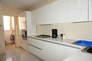 a white kitchen with a stove and a sink at Appartement F3 Almadies vue/mer accès+ Dakar in Dakar