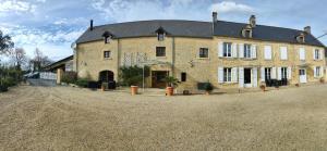 a large brick building on a dirt road at La ferme aux chats in Formigny
