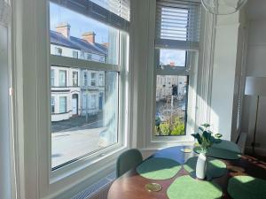 a dining room with a table and two large windows at Luxury 2 Bed Apartment in Portadown