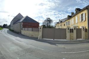 a house with a fence on the side of a street at La ferme aux chats in Formigny