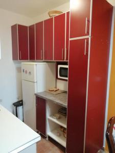 Il comprend une cuisine équipée de placards rouges et d'un réfrigérateur blanc. dans l'établissement N apartman, à Obrenovac