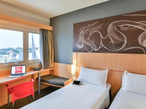 um quarto de hotel com 2 camas e uma secretária com um computador portátil em ibis Goiânia em Goiânia