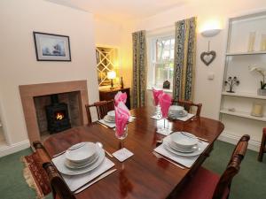 a dining room with a table and a fireplace at Garden Cottage in Penrith