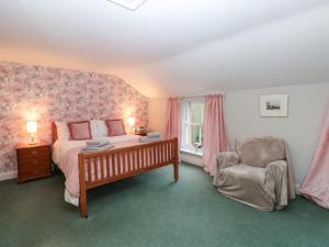 ein Schlafzimmer mit einem Bett und einem Stuhl in der Unterkunft Garden Cottage in Penrith