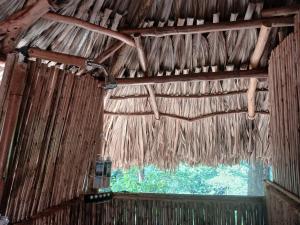 a room with a thatched ceiling with a window at Private waterfall and indigenous house! in Minca
