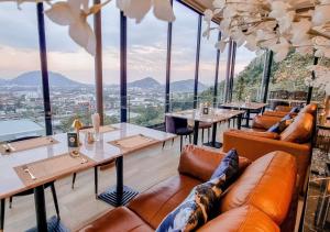 a restaurant with tables and couches and windows at Hilltop Wellness Resort in Phuket
