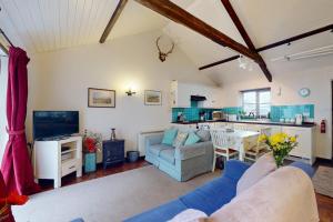 a living room with a couch and a kitchen at Sheepfold Cottage Dulverton in Dulverton