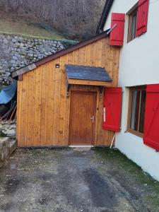 a wooden garage with a wooden door and red shutters at Soupiets in Betpouey