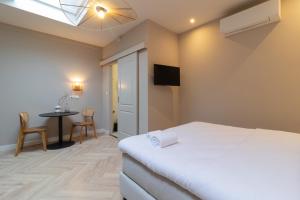 1 dormitorio con cama, mesa y TV en SAYŌ Boutique Hotel en Scheveningen